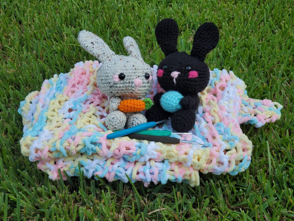 light brown and black bunnies on a blanket in the grass