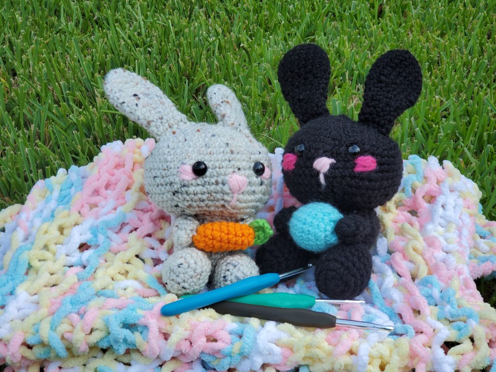 two crocheted bunnies on a blanket