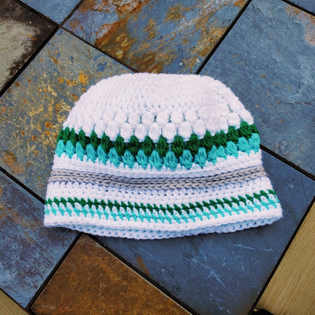 white, emerald, and brown crocheted hat